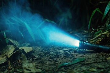 Fototapeta premium Bright Blue Flashlight Illuminating Dark Forest Floor with Mist and Green Grass Creating a Mysterious Atmosphere in Nature