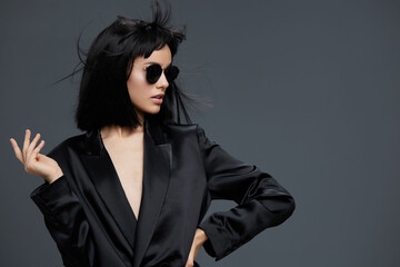 Asian woman, black suit, sunglasses, posing, gray background a stylish asian woman dressed in a sharp black suit and fashionable sunglasses poses confidently against a neutral gray backdrop