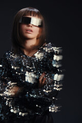 A woman, wearing stylish sunglasses and a shimmering sequin top, poses confidently against a dark...