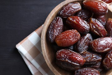 Tasty dried dates on black table, top view