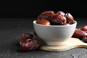 Tasty dried dates in bowl on grey table
