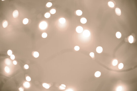 A soft focus image of warm string lights casting an enchanting glow, evoking a cozy atmosphere. The overall tone reflects mocha and mousse shades. Demonstrating color of 2025 year.