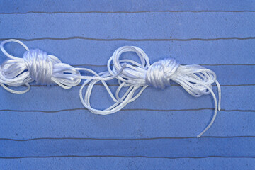 bundled lengths of satiny cord on blank paper viewed from above