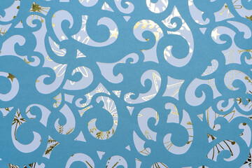 die-cut scrapbooking sheet with ornate swirls on blue decorative paper with gold pattern