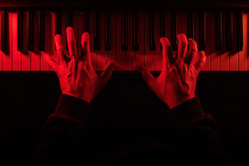 Eerie hands poised on piano keys, illuminated by menacing red light, evoking suspense and dread. The shadowy scene feels like a soundtrack to a horror film or game, embodying fear and unease.