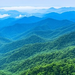 Fototapeta premium Lush green mountain range with hazy blue peaks under a clear sky.