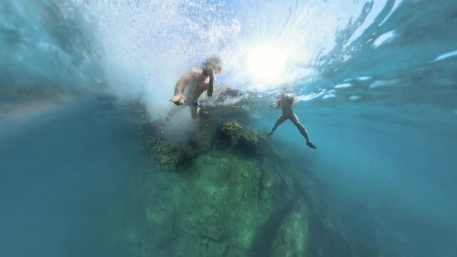 Tiny planet. Underwater shot of a man diving from a cliff into the depths, as he plunges deeper into the water, with sunlight filtering through the surface, illuminating the descent and the surroundin