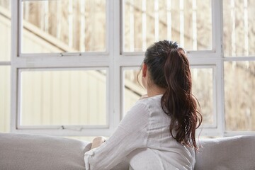 the back of a woman by a window in the sun