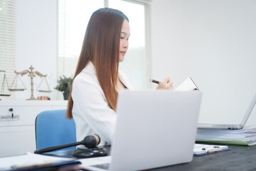A young, professional businesswoman working at her desk in an office, providing online legal...