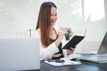A young, professional businesswoman working at her desk in an office, providing online legal...