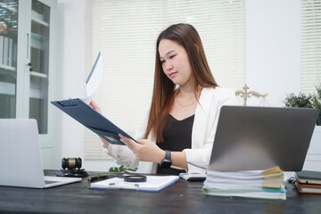 A young, professional businesswoman working at her desk in an office, providing online legal...