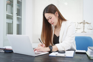 A young, professional businesswoman working at her desk in an office, providing online legal...