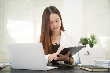 A young, professional businesswoman working at her desk in an office, providing online legal...