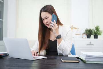 A young, professional businesswoman working at her desk in an office, providing online legal...