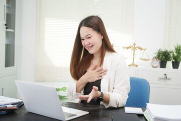 A young, professional businesswoman working at her desk in an office, providing online legal...