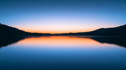 Obraz premium Serene twilight over calm lake with reflections of mountains and sky