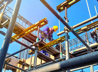 Construction worker assembling scaffolding at a building site. Scaffolding Assembly.