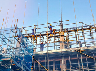 Construction workers on scaffolding building a rooftop structure. Rooftop Construction Crew.