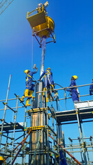 Fototapeta premium Workers using a hoist to lift concrete for a column pour. Lifting Concrete to Heights