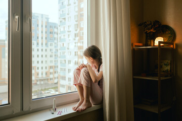 Fototapeta premium A sick teenage girl is sad near the window. Child's skin with many red spot. Allergic reaction, Drug allergy, Scarlet fever, Atopic dermatitis, Diaper rash, Urticaria, Scabies, Heat rash.