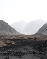 Naklejka premium Scenic view of a barren valley surrounded by mountains and misty skies in early morning light