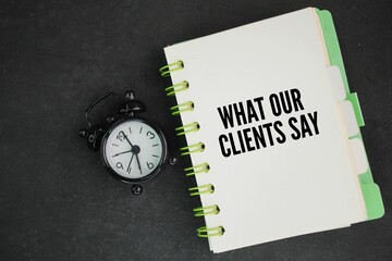 an alarm clock and a book with the words What Our Clients Say. service concept or customer testimonials.