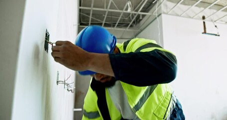 Installation, plug and wires with electrician man on building site for property development. Electrical engineer, industry and maintenance with construction worker in hardhat for safe renovation