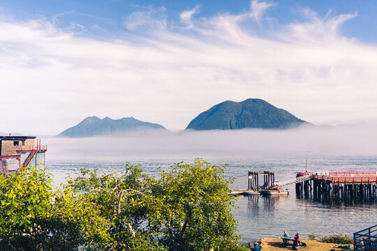 A foggy morning in a Pacific Ocean bay with mountains in the background and the ocean