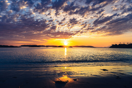Summer sunset on a Pacific Ocean beach with beautiful clouds and the sun reflecting in the water with warm colours