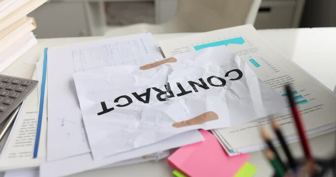 A busy office scene with a crumpled contract among scattered documents and various stationery items