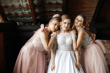 The bridesmaids hug and smile. The background consists of a wooden wall and roof with visible beams.