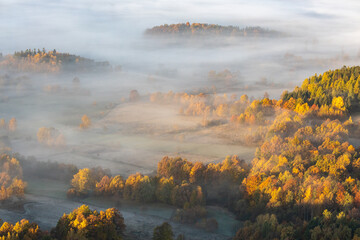 Fototapeta premium Early morning, misty autumn sunrise above hilly forest