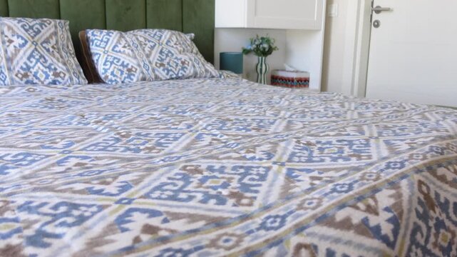 Modern bedroom designed with green accents and a bedspread showcasing intricate patterns