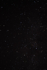 Wide expanse of a starry night sky with an array of bright and dim stars scattered across a deep black background, creating a cosmic view.