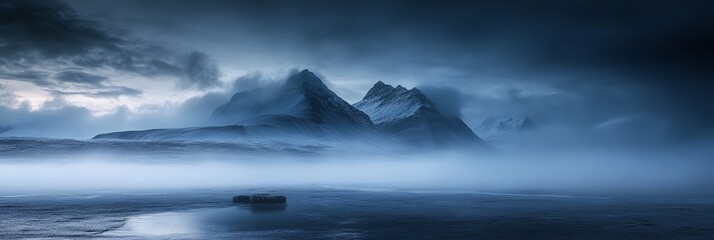 Fototapeta premium A mountain range is visible in the distance with a foggy sky. The mountains are covered in snow and the sky is dark and cloudy. The scene is serene and peaceful, with the fog adding a sense of mystery
