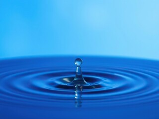 A single crystal clear water drop suspended above the surface of still water, illuminated by soft blue light that dances within the surrounding air, mist, peaceful atmosphere