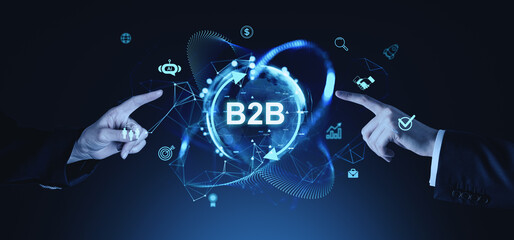 Business hands pointing at "B2B" text surrounded by digital icons and network graphics on a dark blue futuristic background.