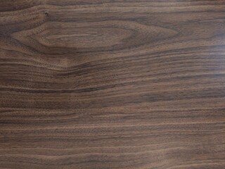 Wooden plank texture with natural grain pattern, dark brown wood surface with natural grain patterns, smooth texture, and polished finish, ideal for furniture or decorative surfaces.