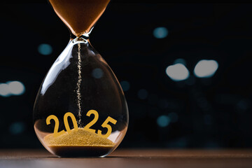 Hourglass with 2025 on dark background with bokeh and copy space for preparation and countdown of...