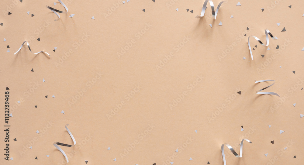 Wall mural close up on group of silver color of rolling ribbon and confetti on beige background with copy space