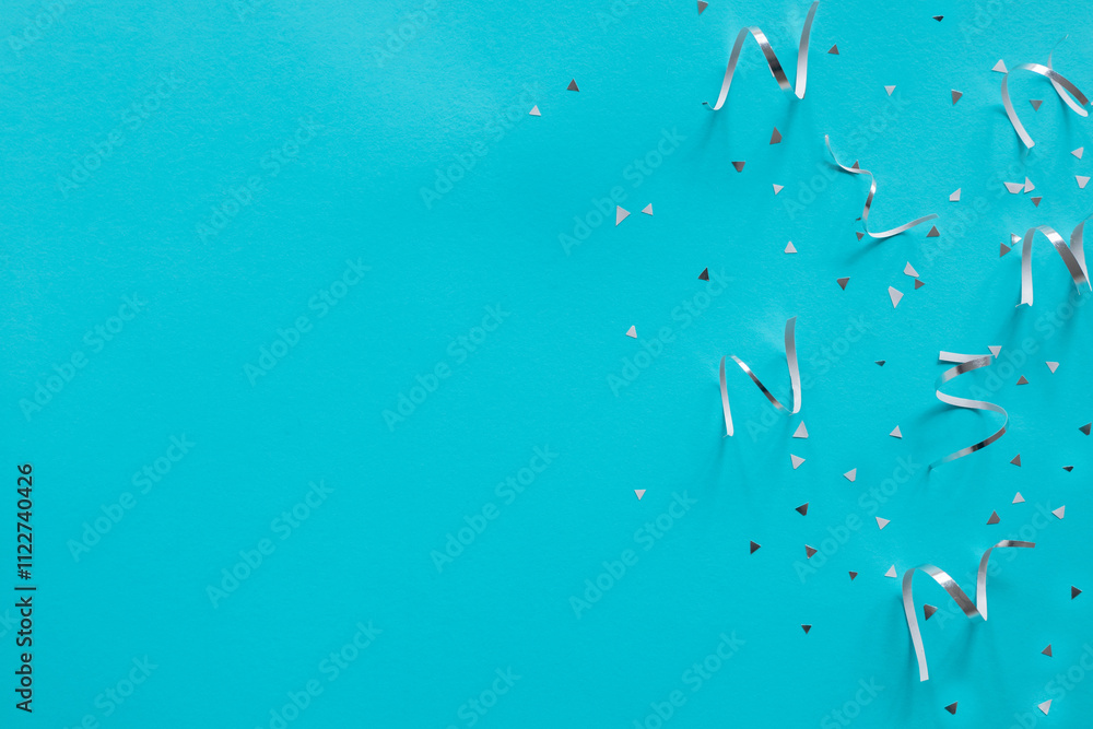 Wall mural close up on group of silver color of rolling ribbon and confetti on teal background with copy space 