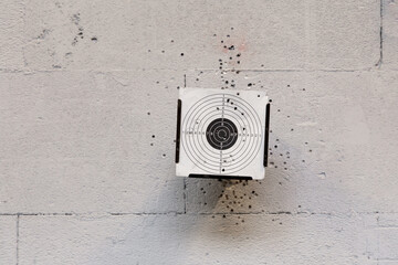 Eine Zielscheibe mit Löchern von Einschüssen. An der Wand an der sich die Zielscheibe befindet,...