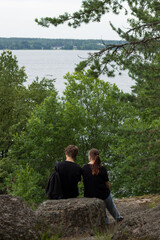 A couple sits on a rock overlooking a river. Vyborg.