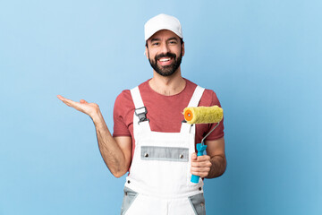 Adult painter man over isolated blue background holding copyspace imaginary on the palm to insert...
