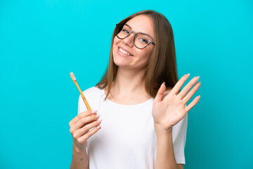 Young Lithuanian woman brushing teeth over isolated background saluting with hand with happy expression