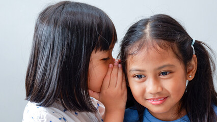 two pretty little girls telling secrets and giggling