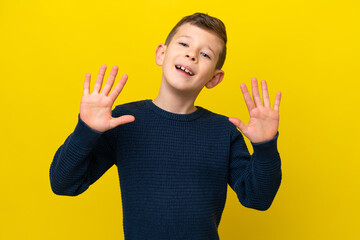 Little caucasian boy isolated on yellow background counting ten with fingers