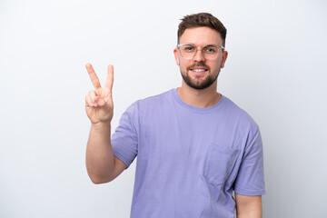 Naklejka premium Young caucasian man isolated on white background smiling and showing victory sign
