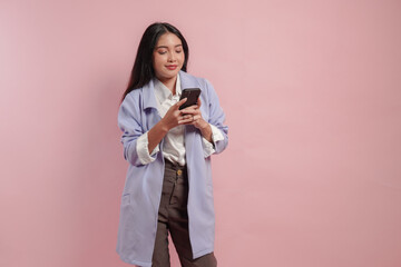 Calm young Asian woman wearing purple coat holding and typing on her smartphone.