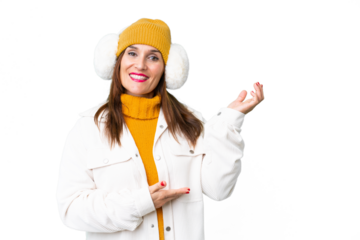 Middle age woman wearing winter muffs over isolated chroma key background extending hands to the side for inviting to come